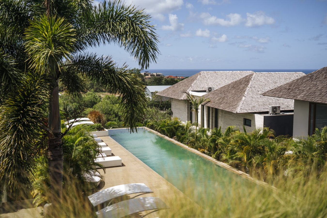 Luxuriöser Pool mit Palmen und Blick auf das Meer